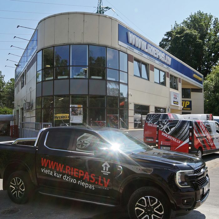 Autoriepu nama ēka ar firmas auto pie ieejas